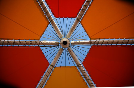 オレンジ色のテントの中から白い放射状パイプの天井を見る