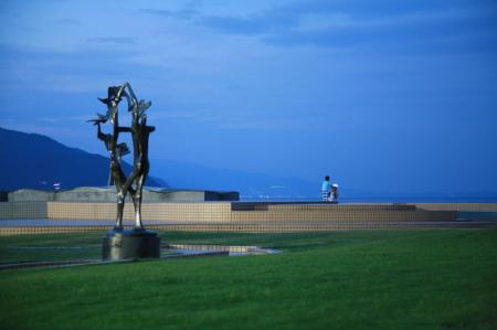 青一面の夕方　海の近くの芝生の公園に黒い彫刻